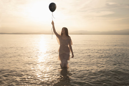 woman holding a black balloon who wants to escape, concept of freedomの写真素材