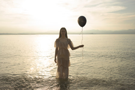 woman holding a black balloon by the string that wants to escape, concept of freedomの写真素材