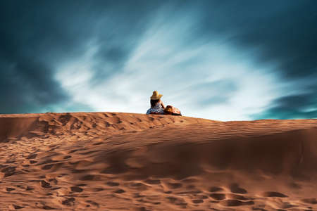 Couple watching the sunset over the dunesの写真素材