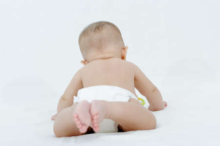 Happy smiling child playing on a white bed, showing her little feetの写真素材