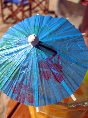 A small decorative blue umbrella on a glass of orange juiceの写真素材