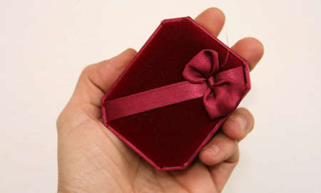A red gift box with a bow held in hand