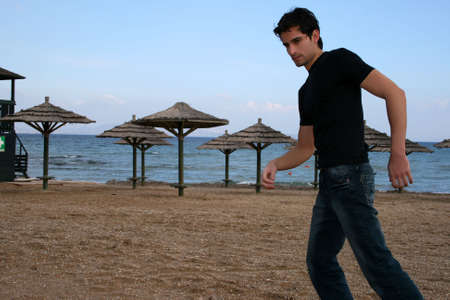 A handsome man walking at the beachの写真素材