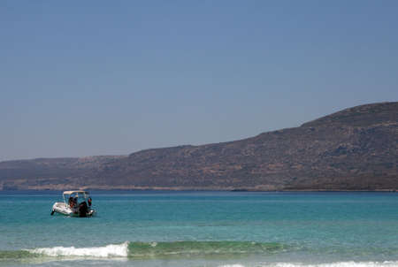 A motor boat sailing towards a sandy beachの写真素材