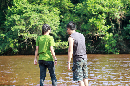 Happy young couple walking by the river in natureの写真素材