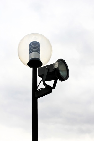 Street lamppost with one spotlight on the backdrop of cloudy sky.の写真素材
