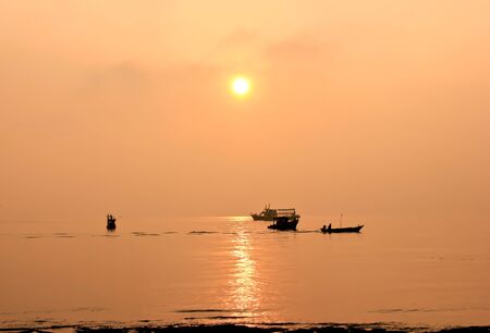 Silhouette of fishing boat in sunrise over the sea on seaside の写真素材