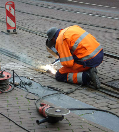 worker with protective mask and gloves welding train rail and sparks spreadingの写真素材