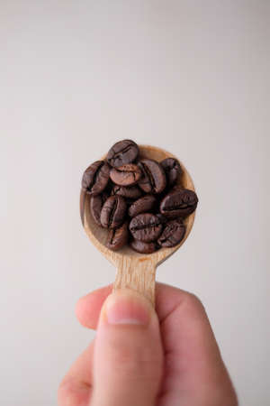 Wooden spoon filled with coffee beansの写真素材