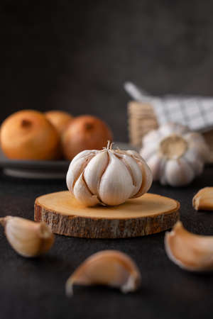 Organic garlic on wooden cutting board with onion and dark backgroundの写真素材