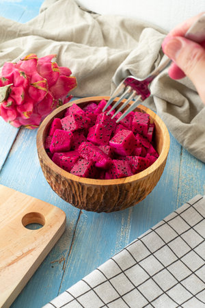 Fresh tropical fruits, sliced cube dragon fruits on blue wooden background and wooden bowlの写真素材