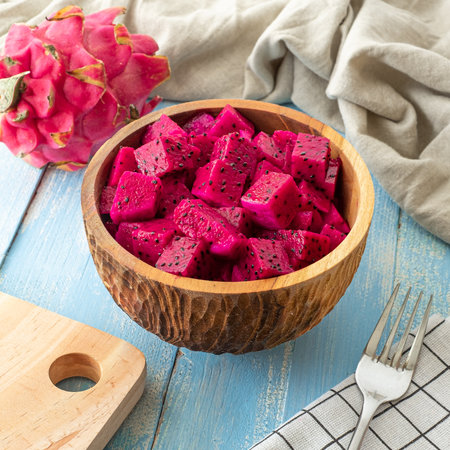 Fresh tropical fruits, sliced cube dragon fruits on blue wooden background and wooden bowlの写真素材