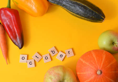 The month of October is written in wooden letters. The calendar. Fall. Vegetables on a yellow background. Harvest.の写真素材
