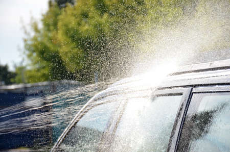 Black car washed with shampoo. Water pours onto the roof of the car.の写真素材