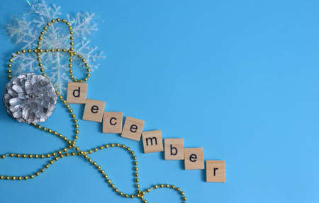 December month written in wooden letters on a blue background. The calendar. Winter. Pine cone, snowflake and beads on the background.の写真素材