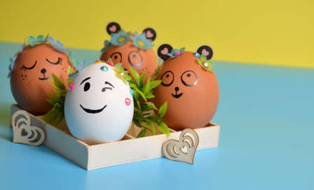 Easter eggs with funny faces in a box on a yellow-blue background. Easter.