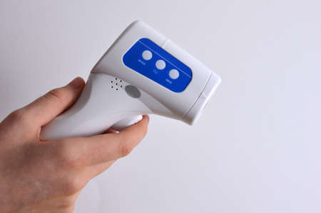 Non-contact thermometer in hands on a white background.