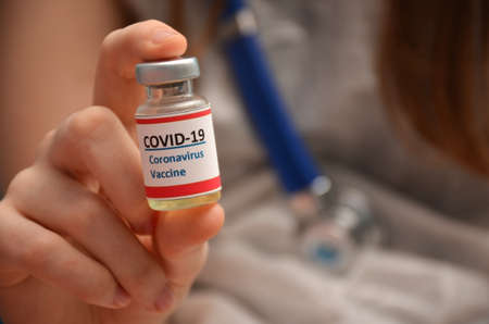 A vial with a coronavirus vaccine and in the hands of a doctor.の写真素材