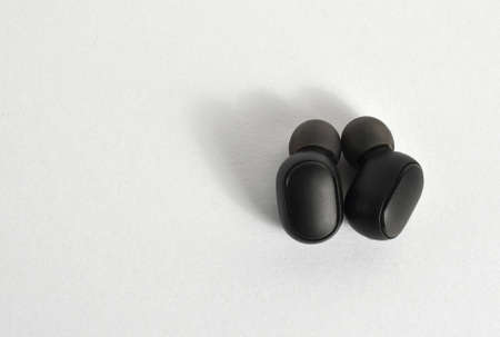 Small black wireless headphones, on a white background
