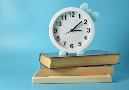 Watch with bow on book. Blue background.の写真素材