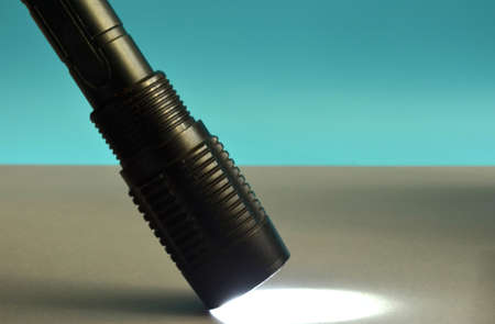 A black flashlight shines on a gray background.