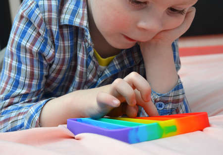 Little Boy lies on the bed and plays with toy.の写真素材