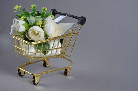 White flowers in a grocery cart on a gray background.の写真素材