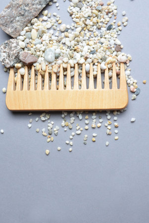 A beautifully crafted Wooden Comb adorned with Decorative Pebbles set against a Gray Backgroundの写真素材