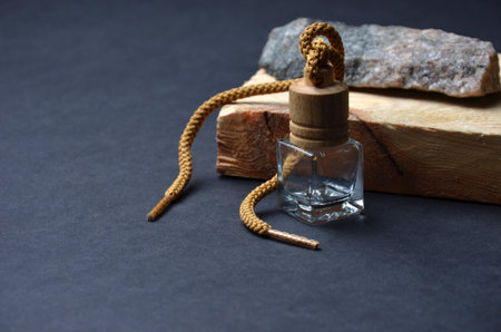 Glass bottle on a black background. Gray stone. Wooden board.