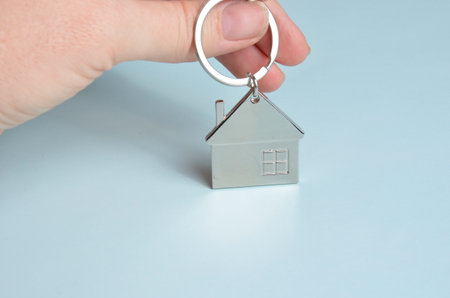 Metal keychain in the shape of a house. Blue background