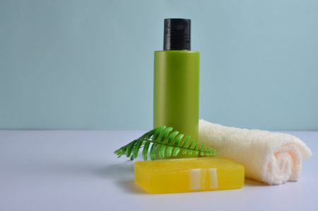 Cosmetic bottle, green sprig, soap and white napkin on a blue background.の写真素材