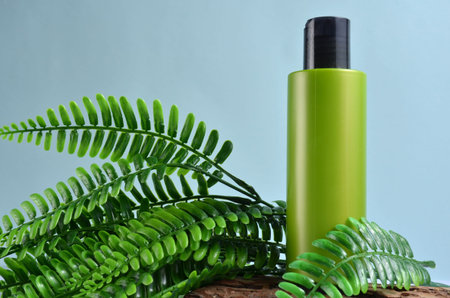 Green bottle and green fern on a blue background.