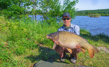 Happy fisherman with carp trophyの写真素材