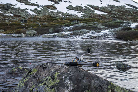 Fishing rod on the stone. River and mountains in Norwayの写真素材