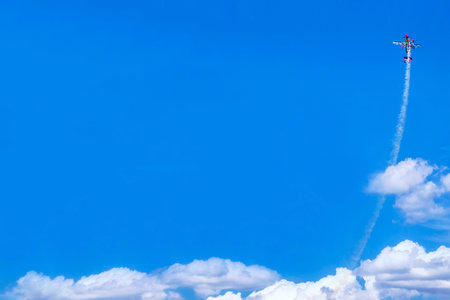 Blue background. Plane climbs above clouds. Airplane flying high in blue sky
