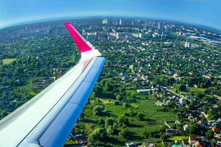 Wing of plane on village background. Flying above city townのeditorial素材