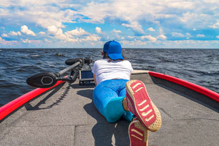 Young woman lie on fishing boat with fish finder, echolot, sonar and structure scaner aboard