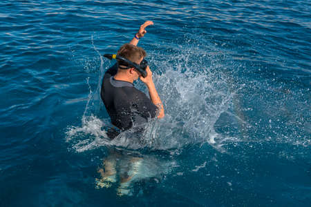 Snorkeling diver jump in sea water with splashing