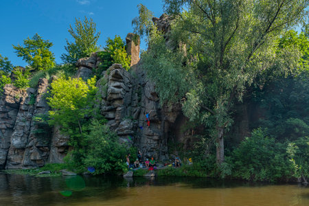 Buky canyon, Ukraine - 28 jun 2020: Climber group have rest near rock wall. Canyon and river among...