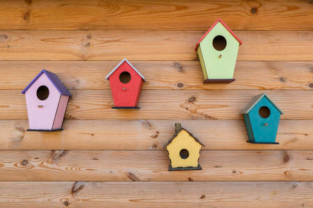 Many bright colored birdhouse and bird feeders on wooden fence. different birdhouses on wallの写真素材