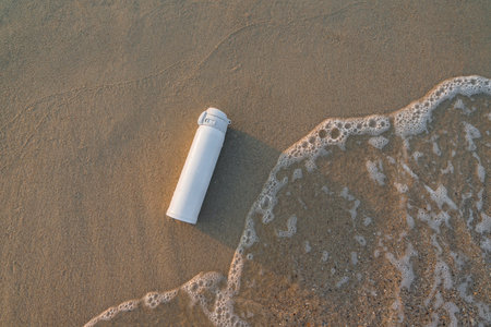 White reusable steel stainless thermo water bottle on sand on sea beach.の写真素材