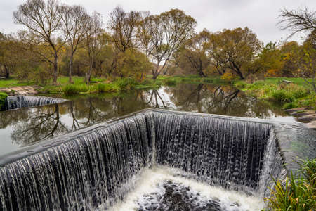 Dam sluice on small river. Gateway channel with waterfall and water flowing rapids to control level...