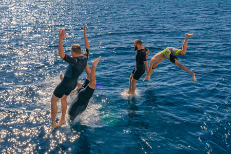 Sharm El Sheikh, Egypt - 23 Dec 2019: Fly after jump. Men's group jumping from yacht into blue sea water for dive. summer fun lifestyleのeditorial素材