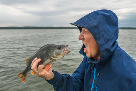 Emotional fishing. fisherman scream at perch fishの写真素材