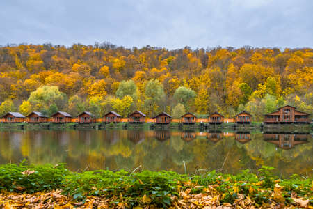 Cottages on lake shore in autumn forest. Country guesthousesの写真素材