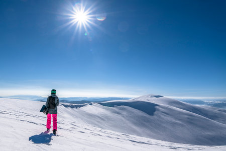 Snowboarder woman with snowboard in hand on mountain top. Winter freeride snowboardingの写真素材