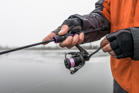 Fishing rod and reel. Hands of fisherman with fishing tackles