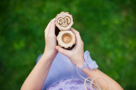 Engagement rings in a decorative wooden box at a girl in handの写真素材