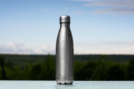 Thermos bottle sprayed with water. Against the sky background. Water tumbler.の写真素材