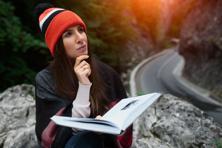 Hipster beautiful and travel girl reading a book in mountains.